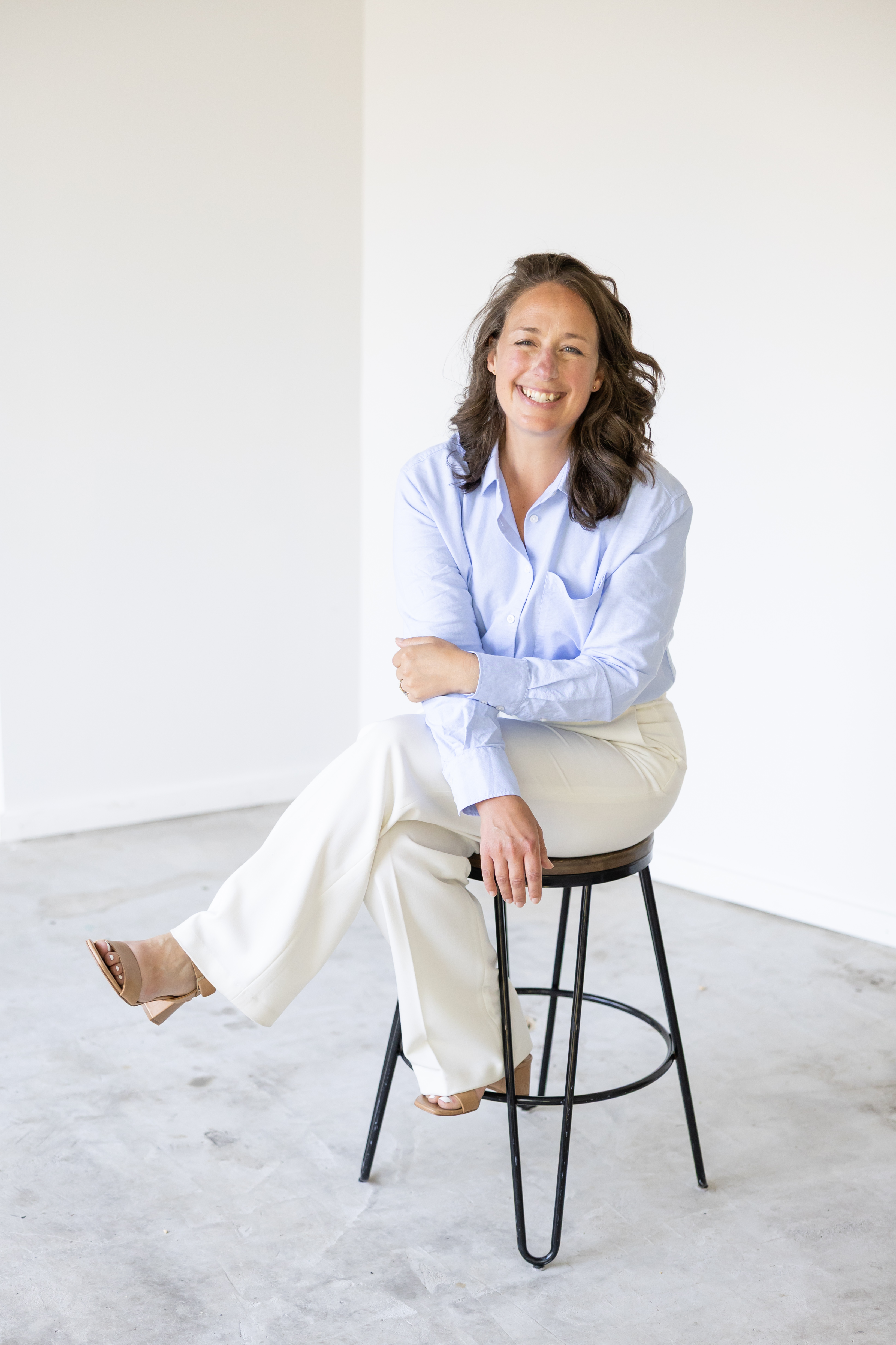 Liz sitting on a stool in a bright studio