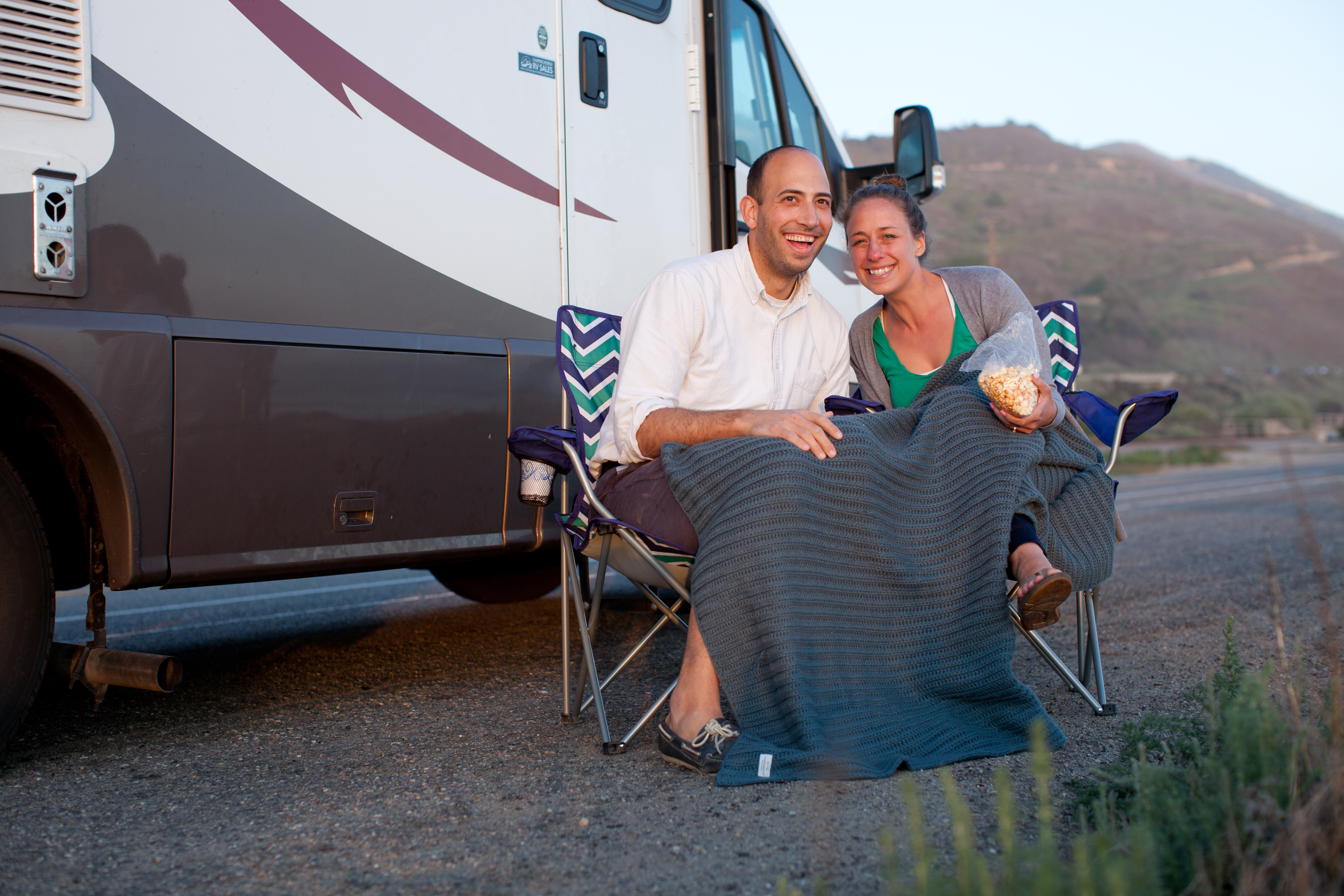 Liz and Ryan sharing popcorn outside their RV at sunset