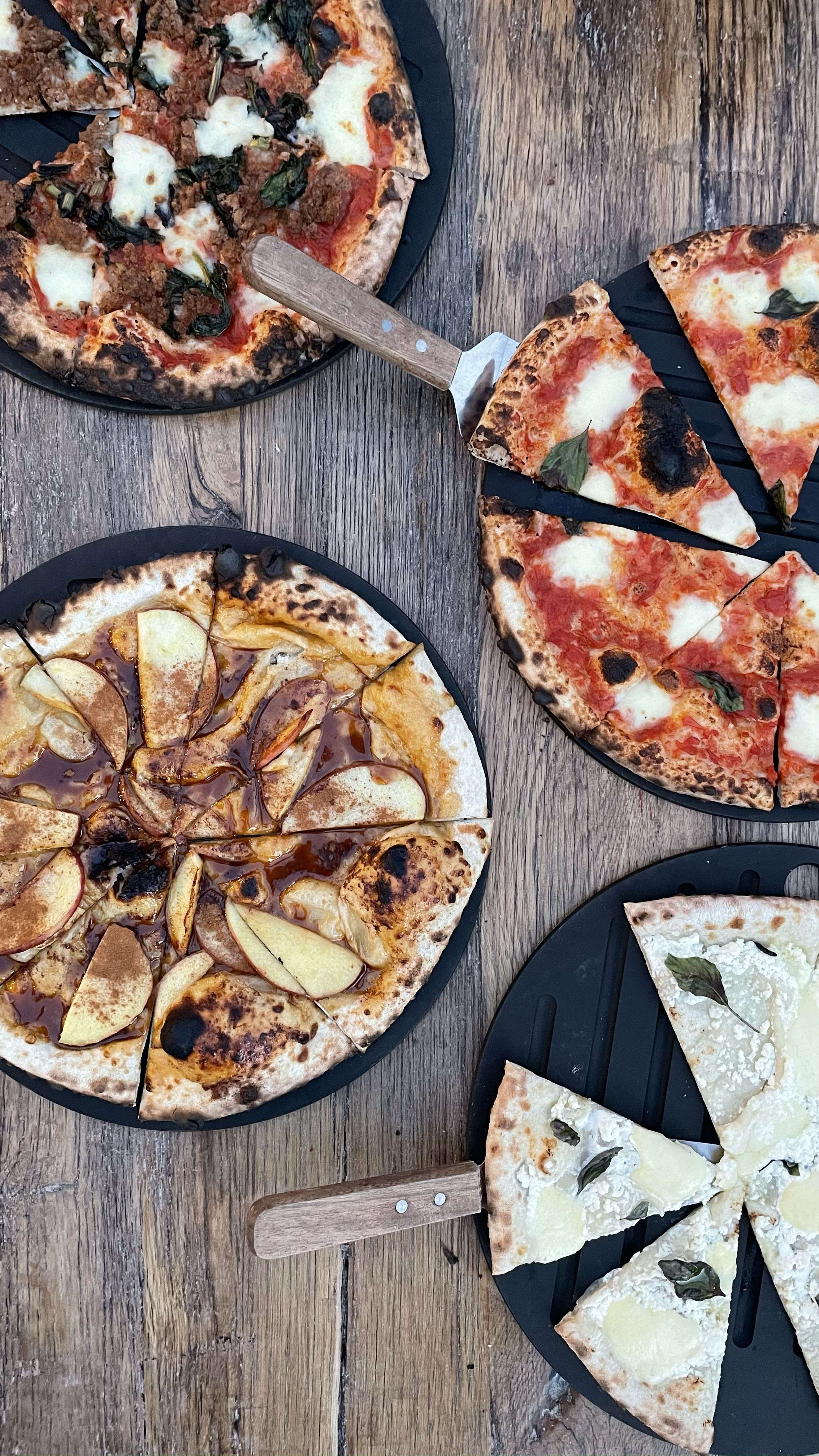 Four artisan pizzas on a wooden table