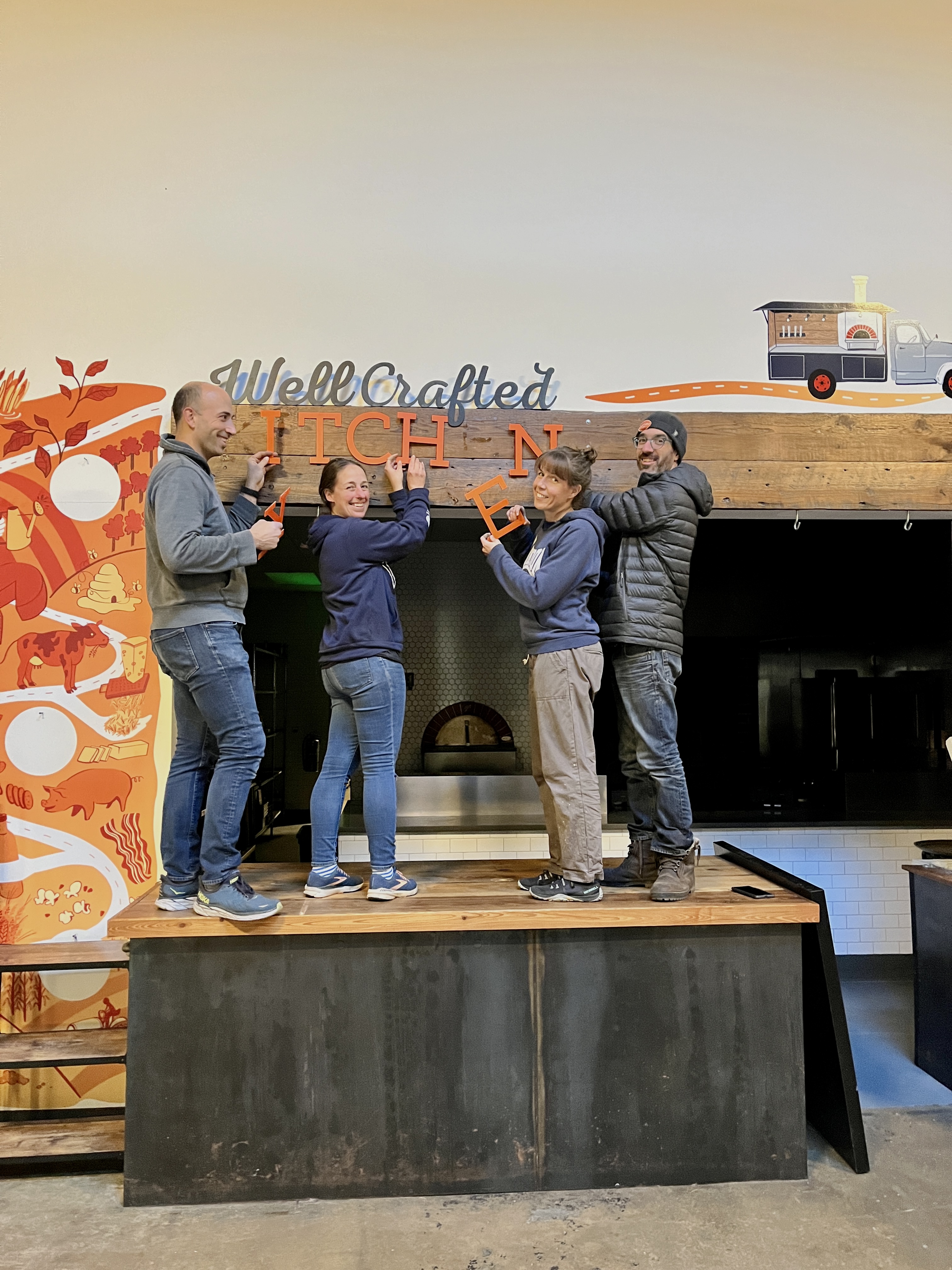 The Well Crafted team installing the kitchen sign at Union Craft Brewing
