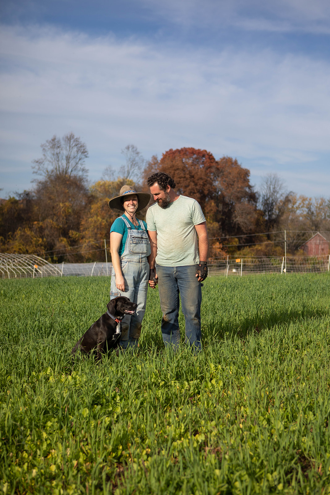 Christy and Connor with their dog in a green farm field